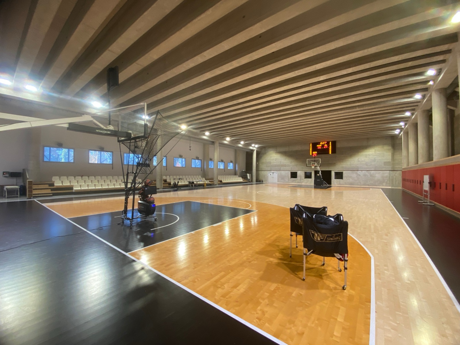 La salle d&rsquo;entra&icirc;nement avec son parquet en deux teintes, ses chariots de ballons et sa machine de tir sous le panier